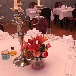 gedeckter Tisch mit Kerzenhalter und Blumenschmuck bei Ben - das Restaurant